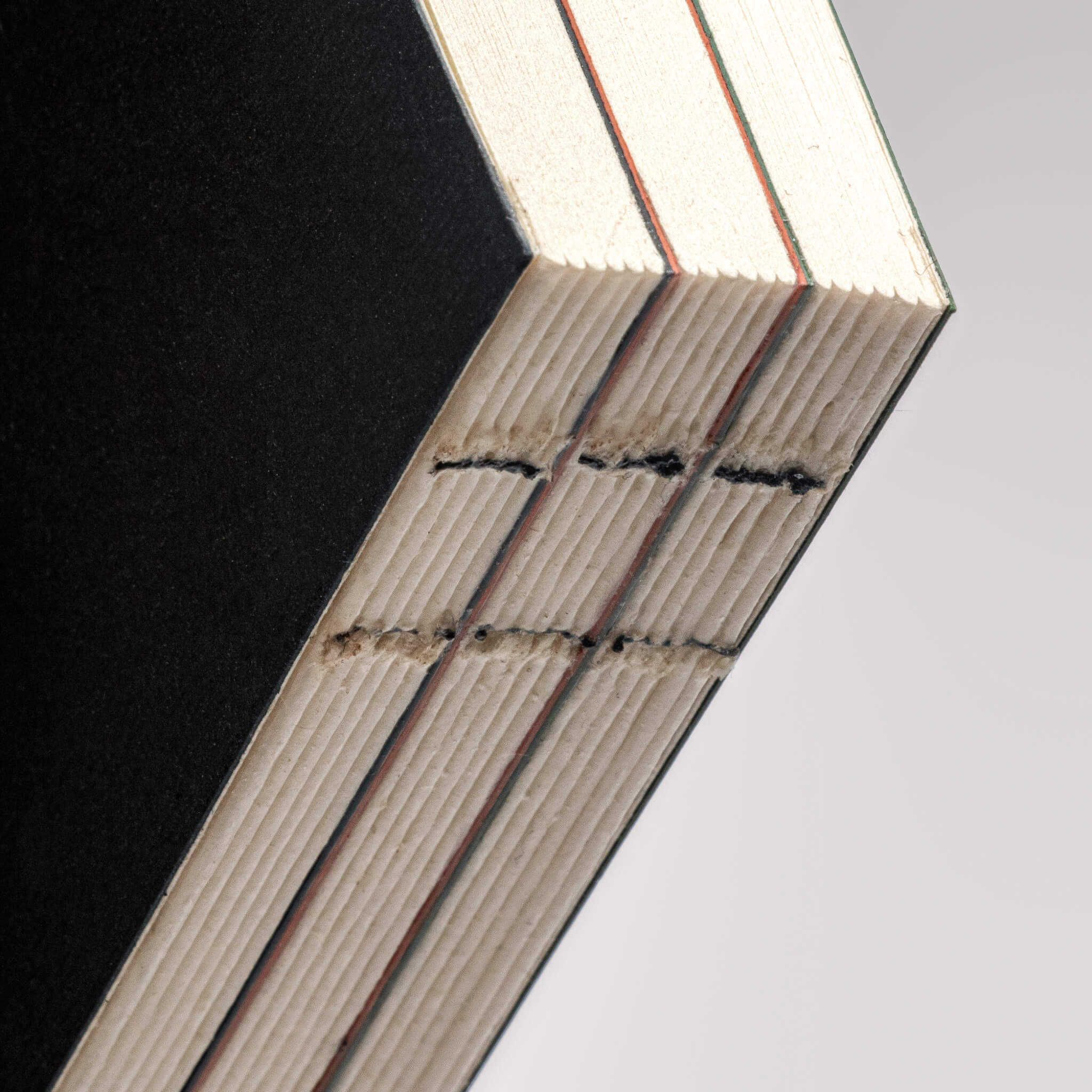 Close-up of basenotes 0144 notebook spine showing exposed hand-sewn binding and precise stitch alignment.