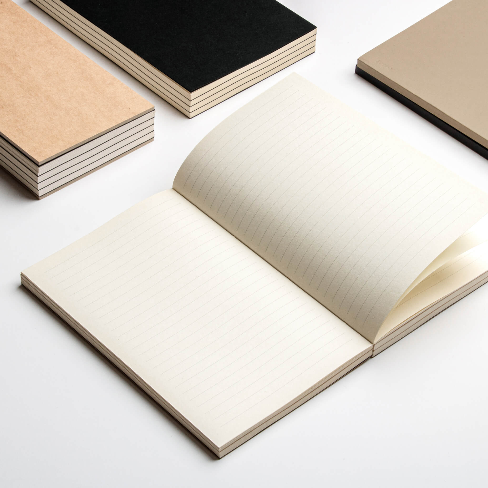 Open basenotes 0432 Notebook with other kraft and black editions stacked beside it on a white background.