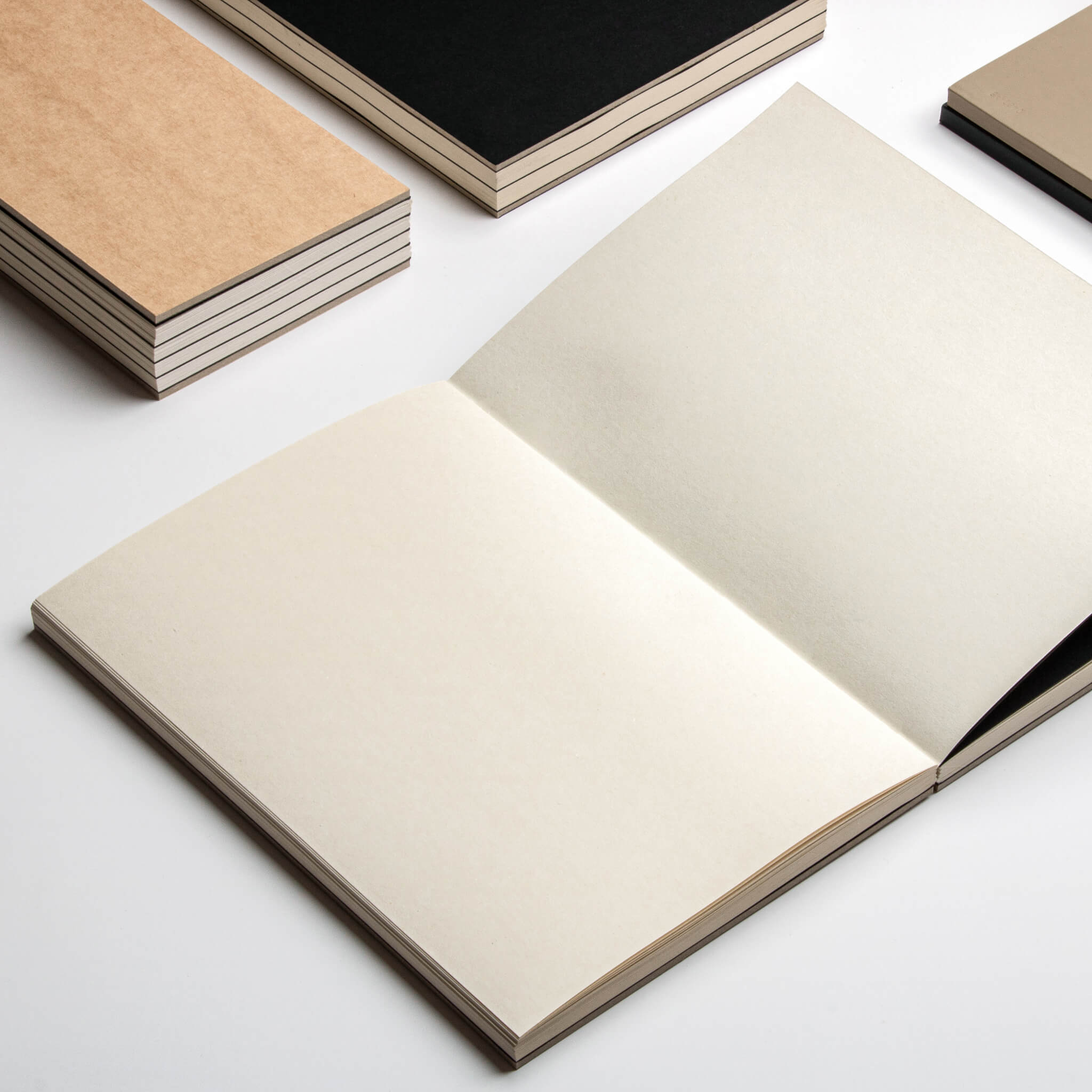 Collection of basenotes 1623 Paperbooks in beige, black, and kraft, showcasing lay-flat design and textured paper.