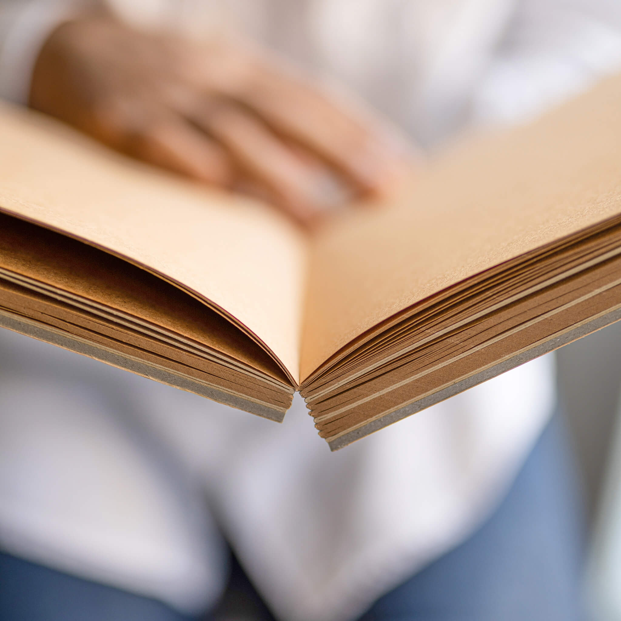 Close-up of the basenotes 1623K Kraft Paper book opened flat, showing visible thread stitching along the spine.