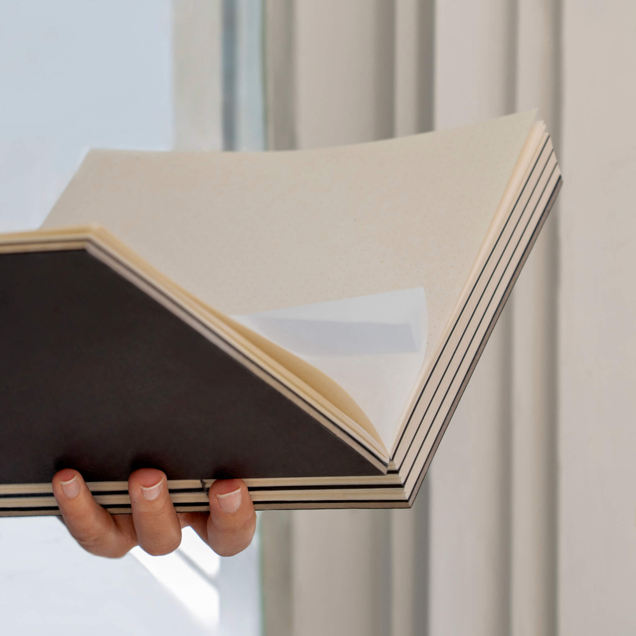 basenotes 2222 Paperbook with black cover held open, showcasing smooth sustainable pages and durable handmade binding.