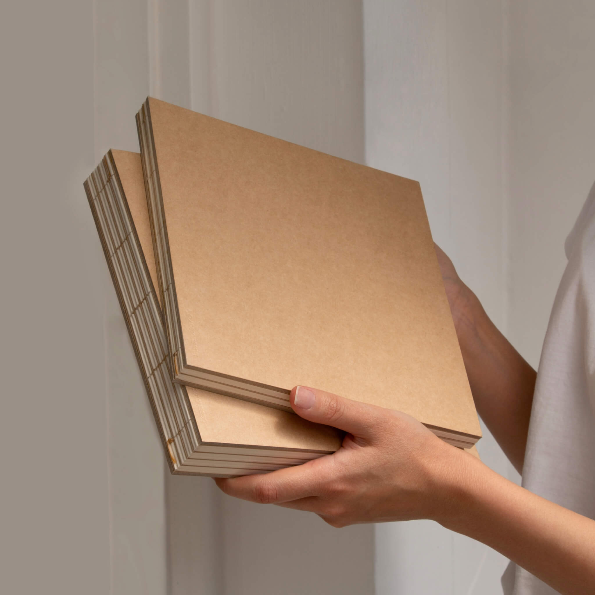 Person holding a set of basenotes 2222 Paperbooks with kraft covers, eco-conscious handmade notebooks designed for creativity.