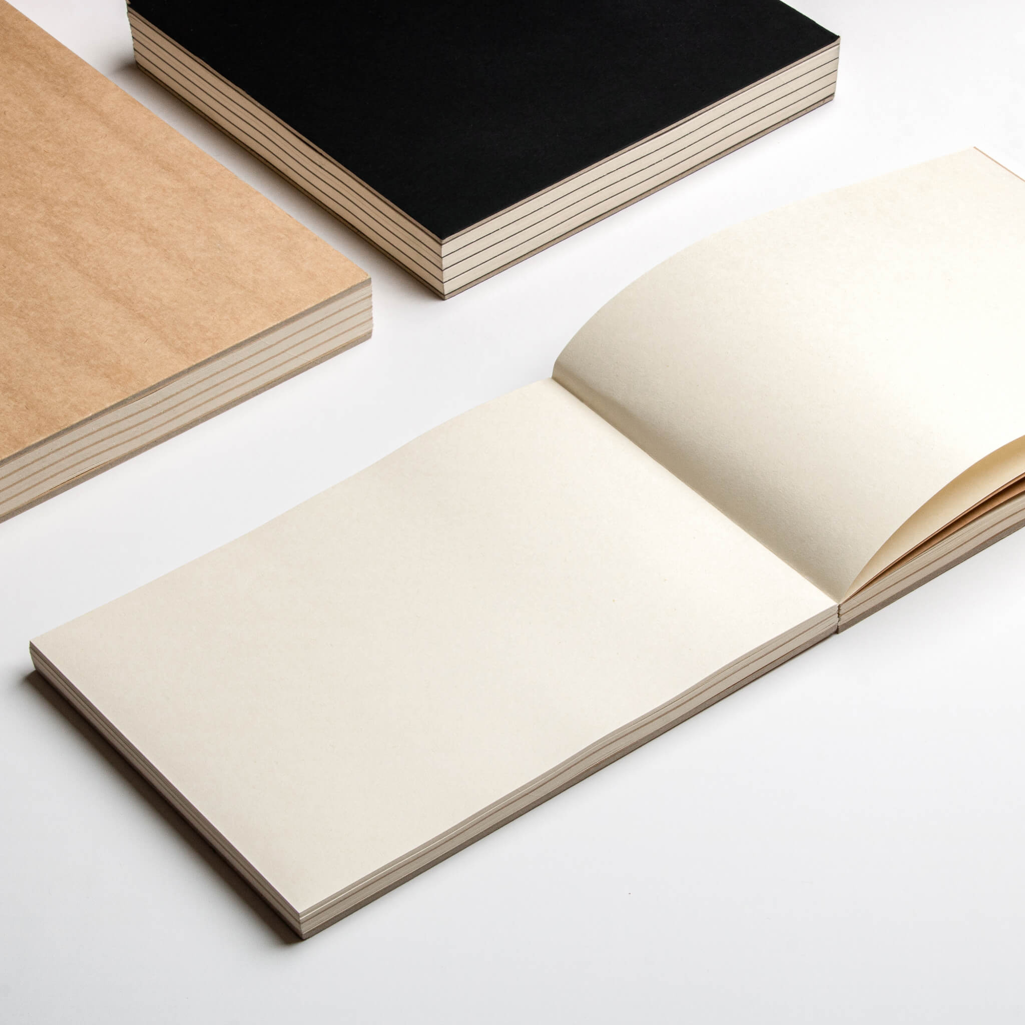 basenotes 2316 sketchbooks in kraft and black covers shown open with cream paper, laid on a clean background.
