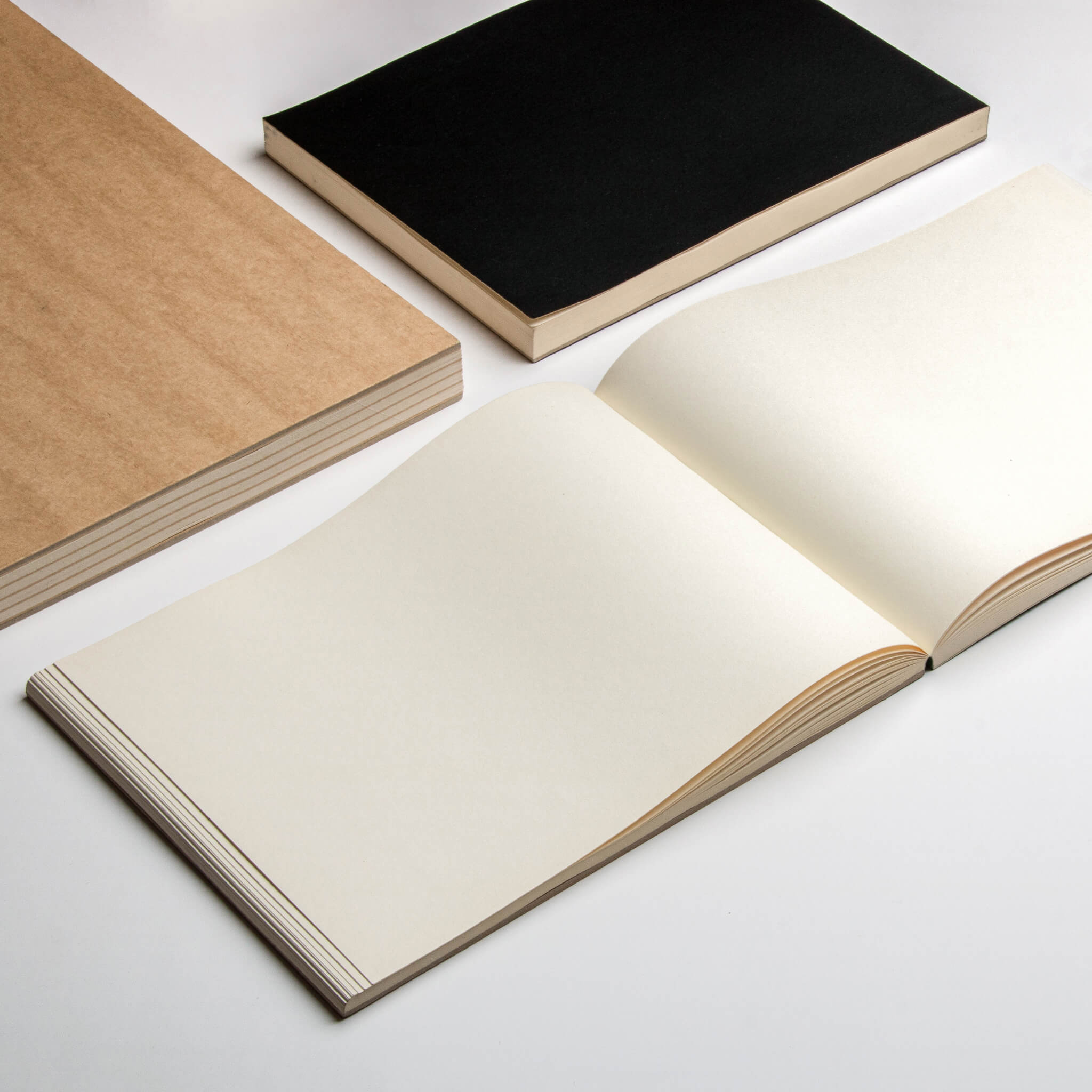 Flat-lay of basenotes 2721 notebooks showing open cream-toned pages with black and kraft softcovers.