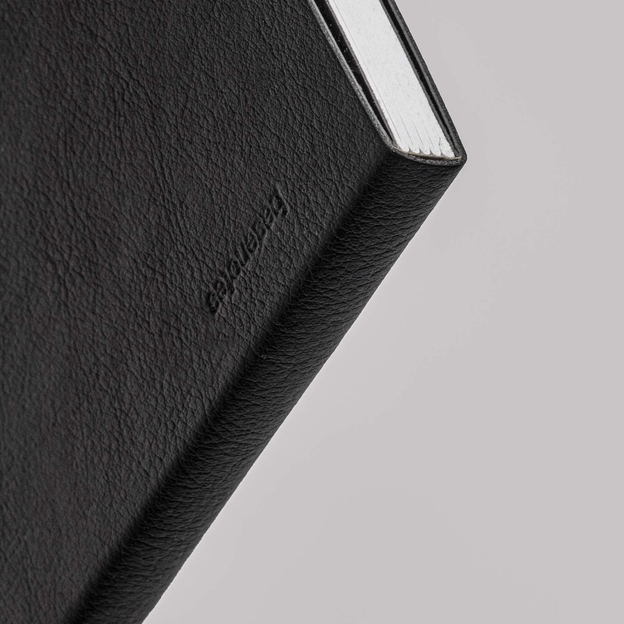Macro image of the basenotes 4000 A5 Notebook’s spine, showing the embossed Basenotes logo and textured cover material.