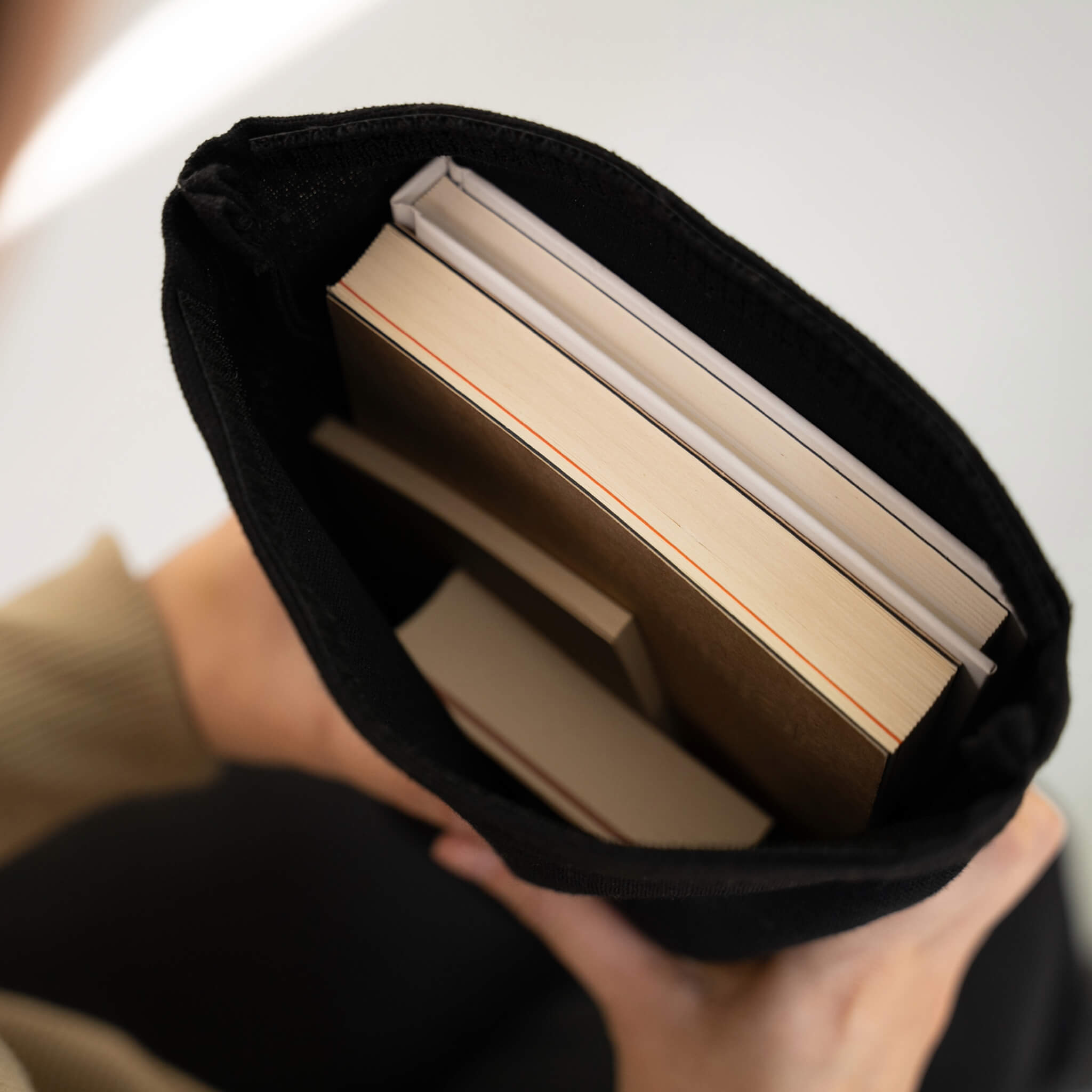Black fabric notebook cover holding multiple basenotes notebooks in A4 and A5 sizes, shown from above in hand