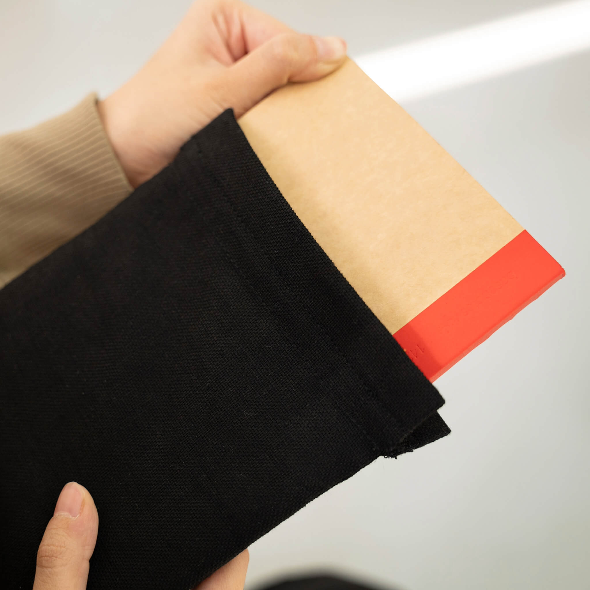 Detail view of a basenotes notebook being inserted into a black fabric notebook cover