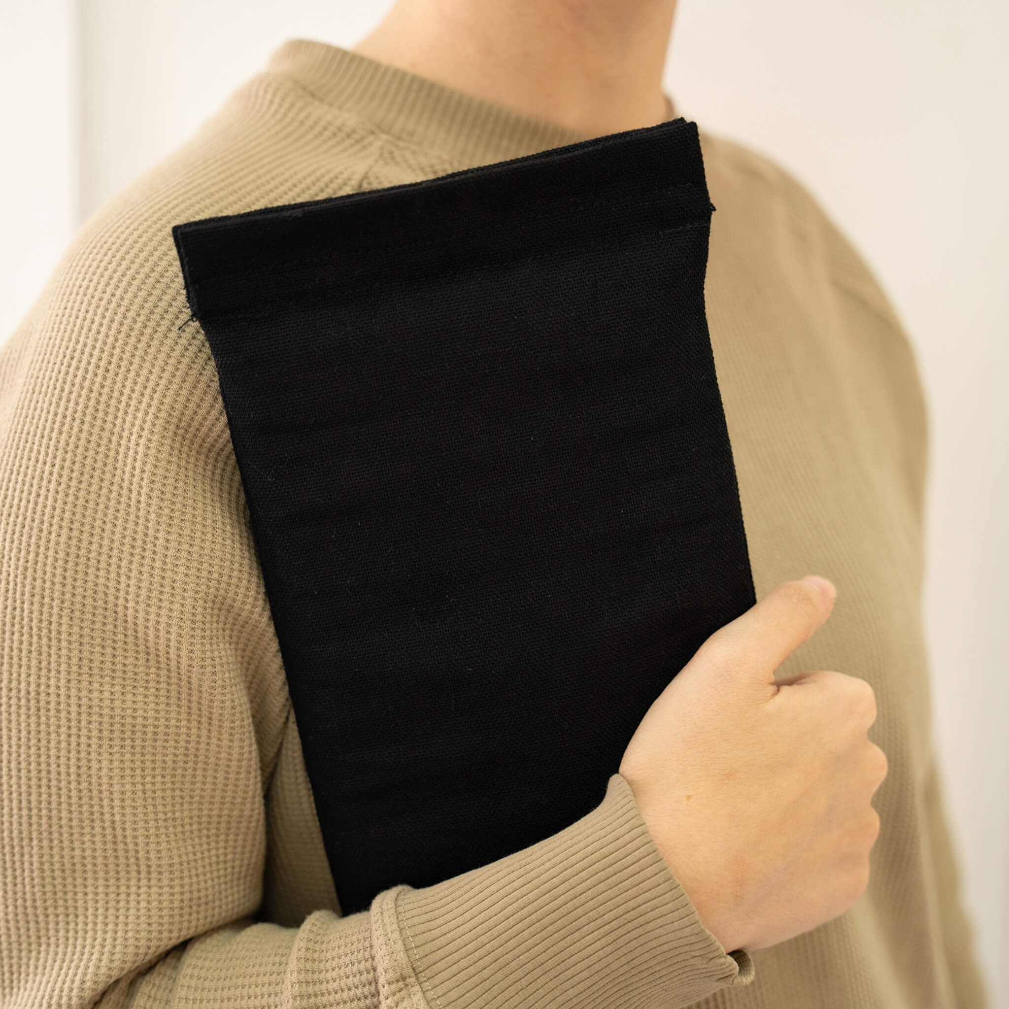 basenotes black fabric notebook cover carried by hand against the body, minimal lifestyle view