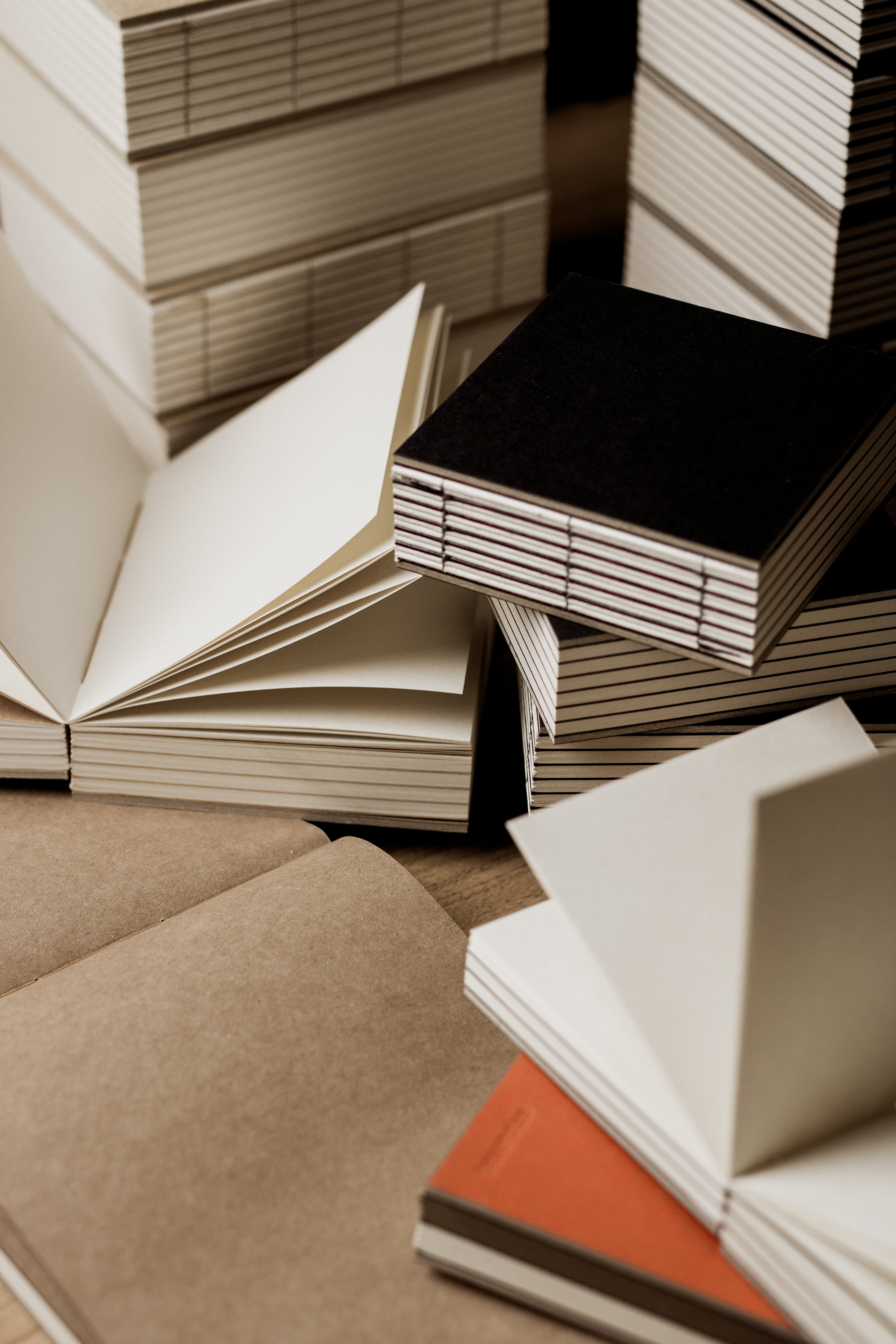 basenotes handcrafted paperbooks with exposed spine binding, stacked and open to show blank cream pages.