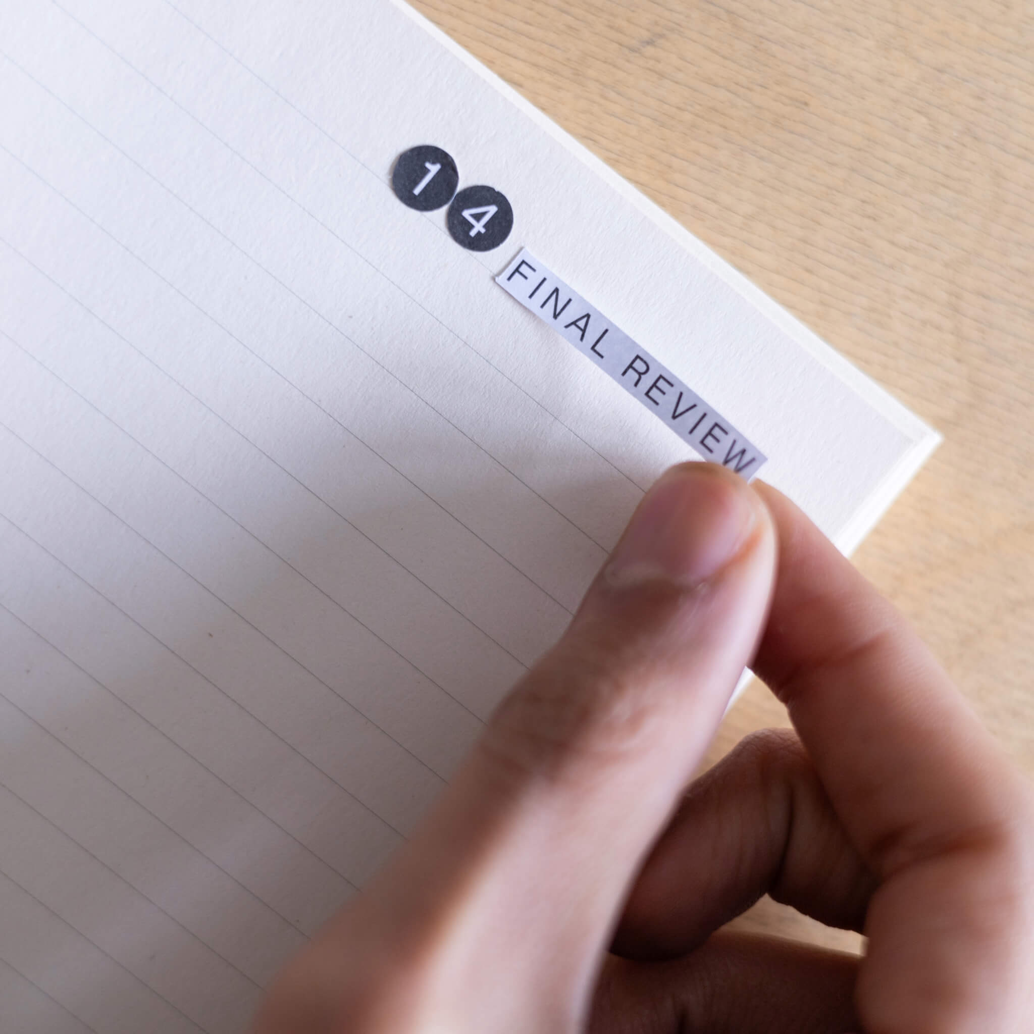 Hand applying a “Final Review” basenotes label sticker onto a lined notebook page