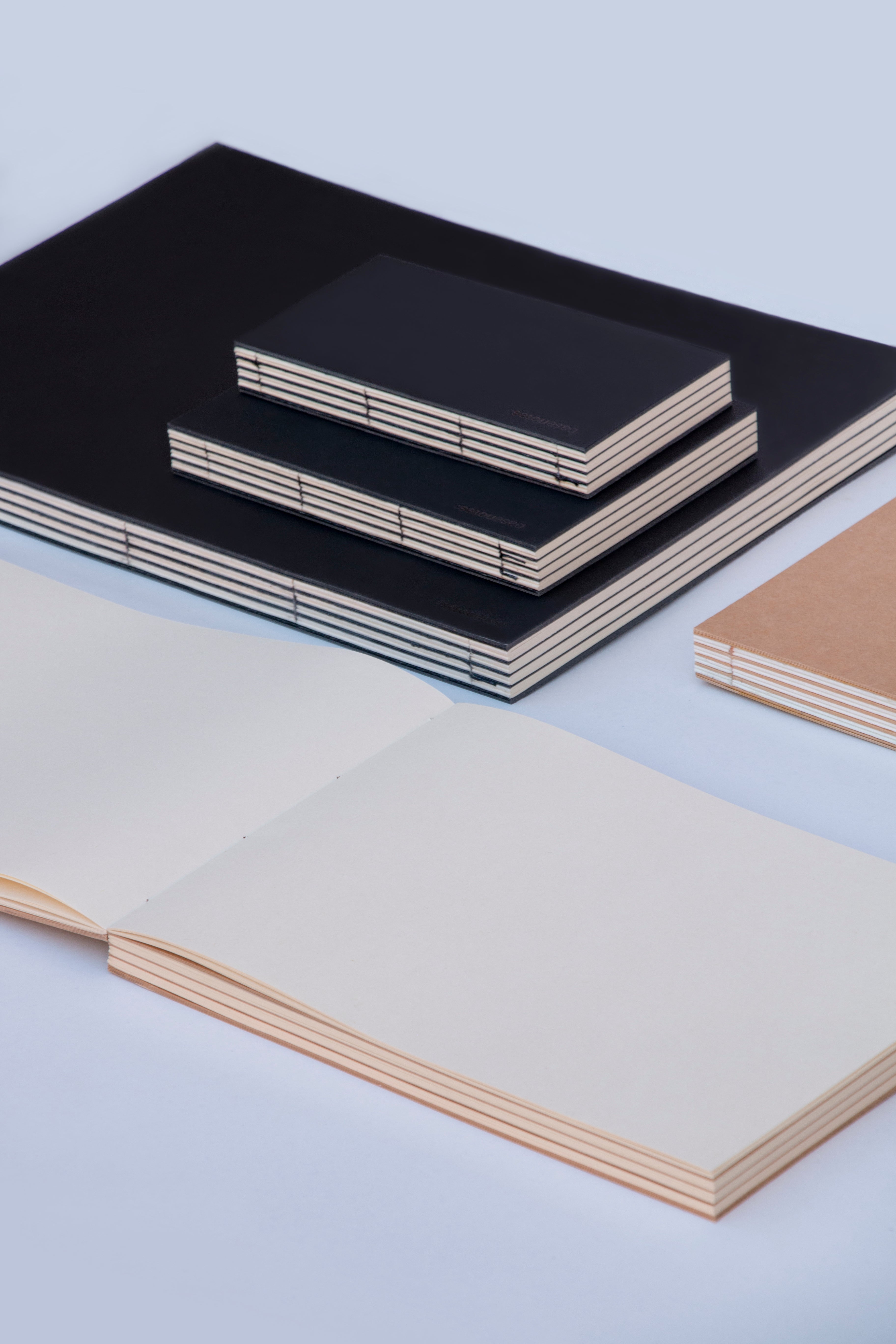 Handmade sketchbooks in varied formats and paper tones, designed for open-ended creative work and experimentation.