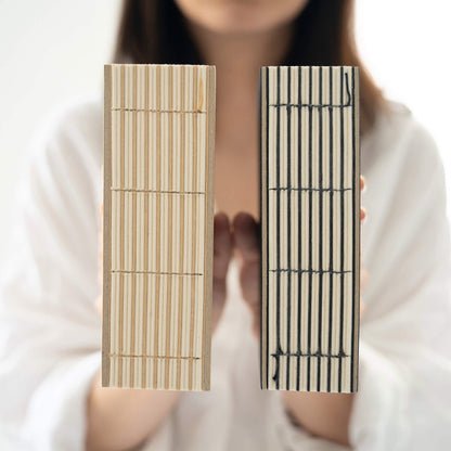 Close-up of basenotes 1216 Paperbooks in Kraft and Black covers, showing detailed exposed hand-stitching on the spines.