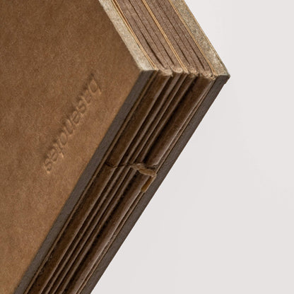 Detail view of a hand-sewn sketchbook spine with exposed stitching and embossed kraft paper cover