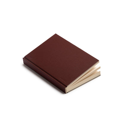 basenotes 0128 Notebook in maroon hardcover shown slightly open with cream pages visible.