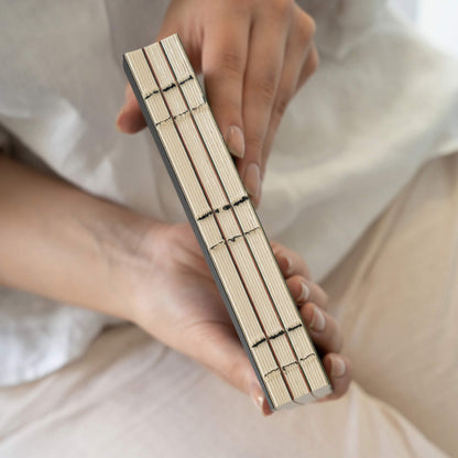 Hand-held view of basenotes 0144 Notebook spine showing exposed black stitching across three sewn sections.