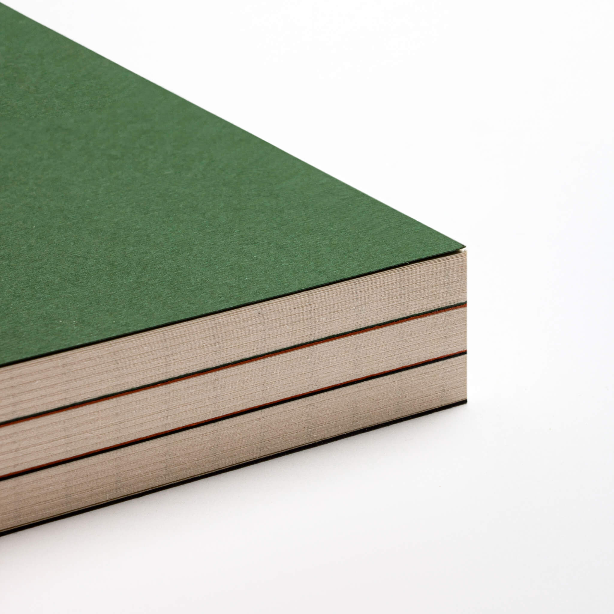 Corner close-up of basenotes 0144 notebook with green cover, showing layered pages and fine paper edges.