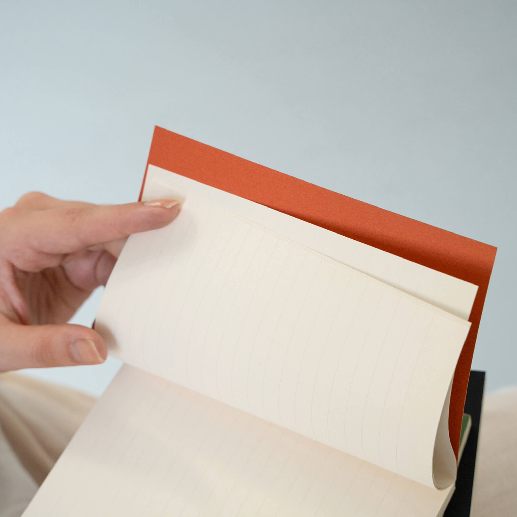 Close-up of basenotes 0144 Notebook pages being flipped, revealing lined acid-free paper in warm ivory tone.
