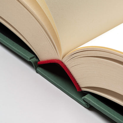 Macro shot of the basenotes 0256 Notebook’s red cloth spine and green hardcover, showing precise binding and smooth paper texture.