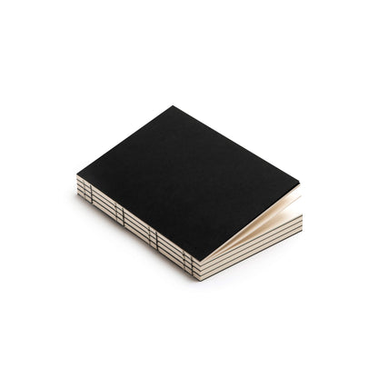 Black basenotes 0432 Notebook photographed flat with visible exposed binding and premium paper edges.