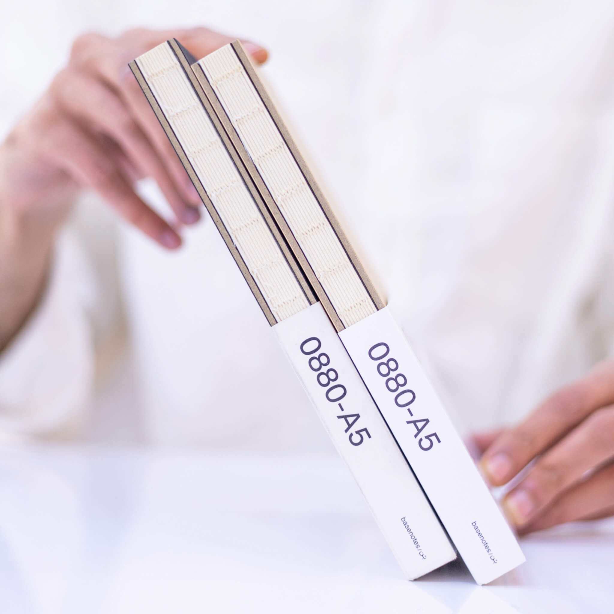 Two basenotes 0880 A5 Notebooks held together, highlighting exposed thread binding and branded paper sleeves.