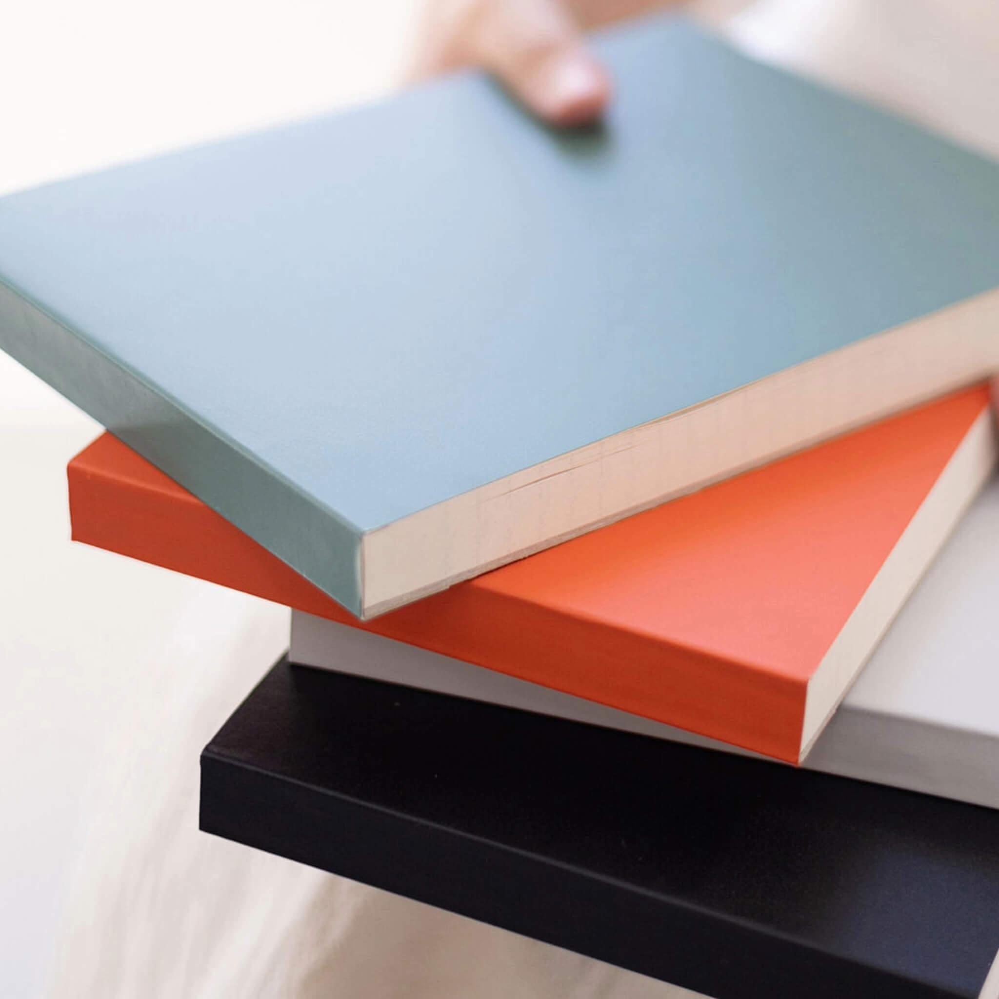 Stack of basenotes 0960 Notebooks in green, orange, black, and light blue covers arranged on a white background.