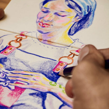 Artist drawing a colourful portrait using coloured pencils in the basenotes 1111 Paper book, showing smooth kraft and white mixed paper texture.