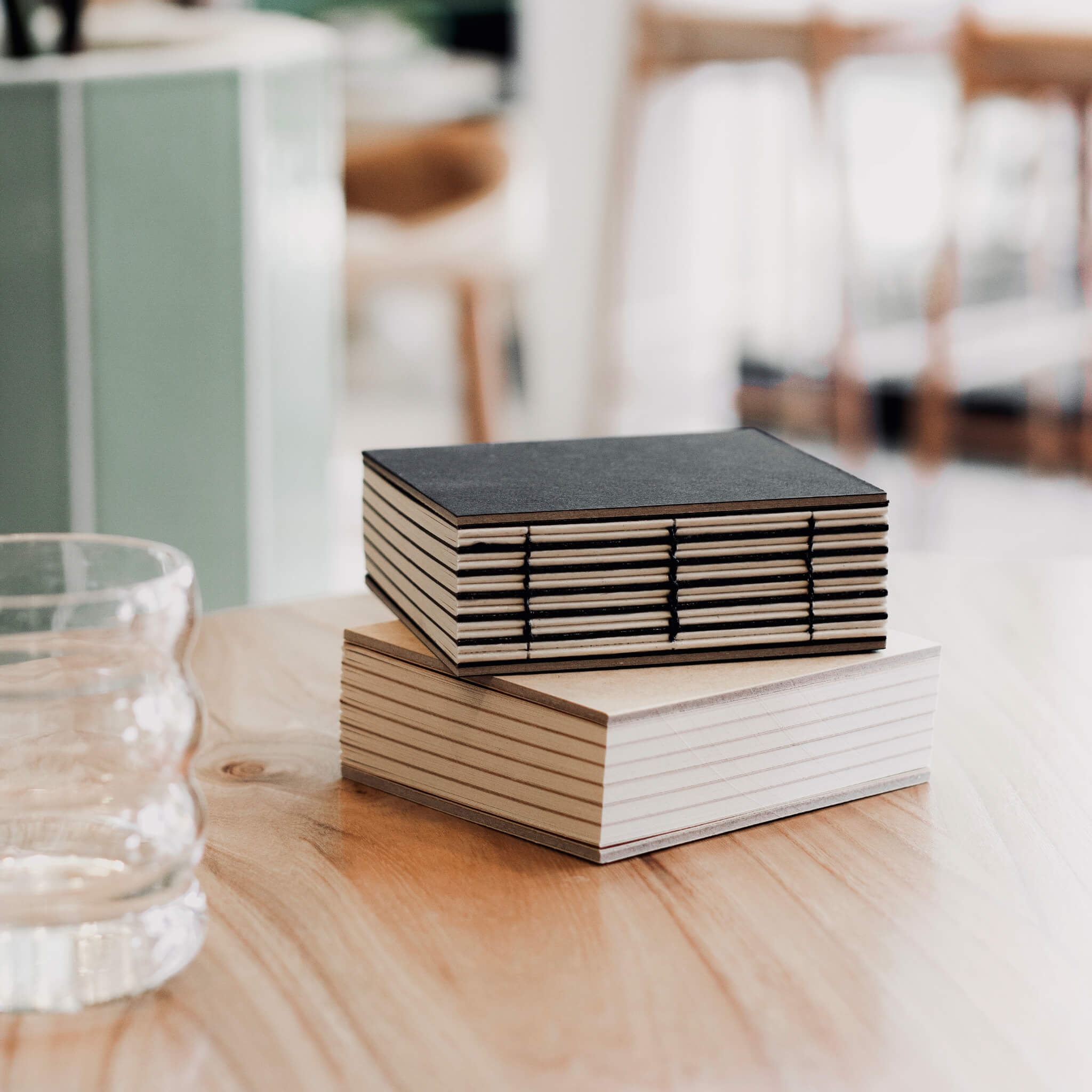 basenotes 1111 handmade square sketchbook featuring a hand-stitched lay-flat binding and acid-free paper, displayed on a wooden table in a bright studio setting.