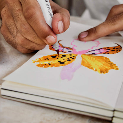 Artist sketching a colourful butterfly illustration using markers on the basenotes 1122 paper book with 127 GSM paper.