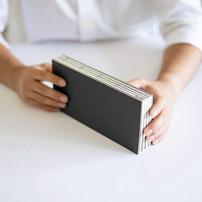 basenotes 1122 Paperbook Black edition held in hand, showing handmade exposed binding
