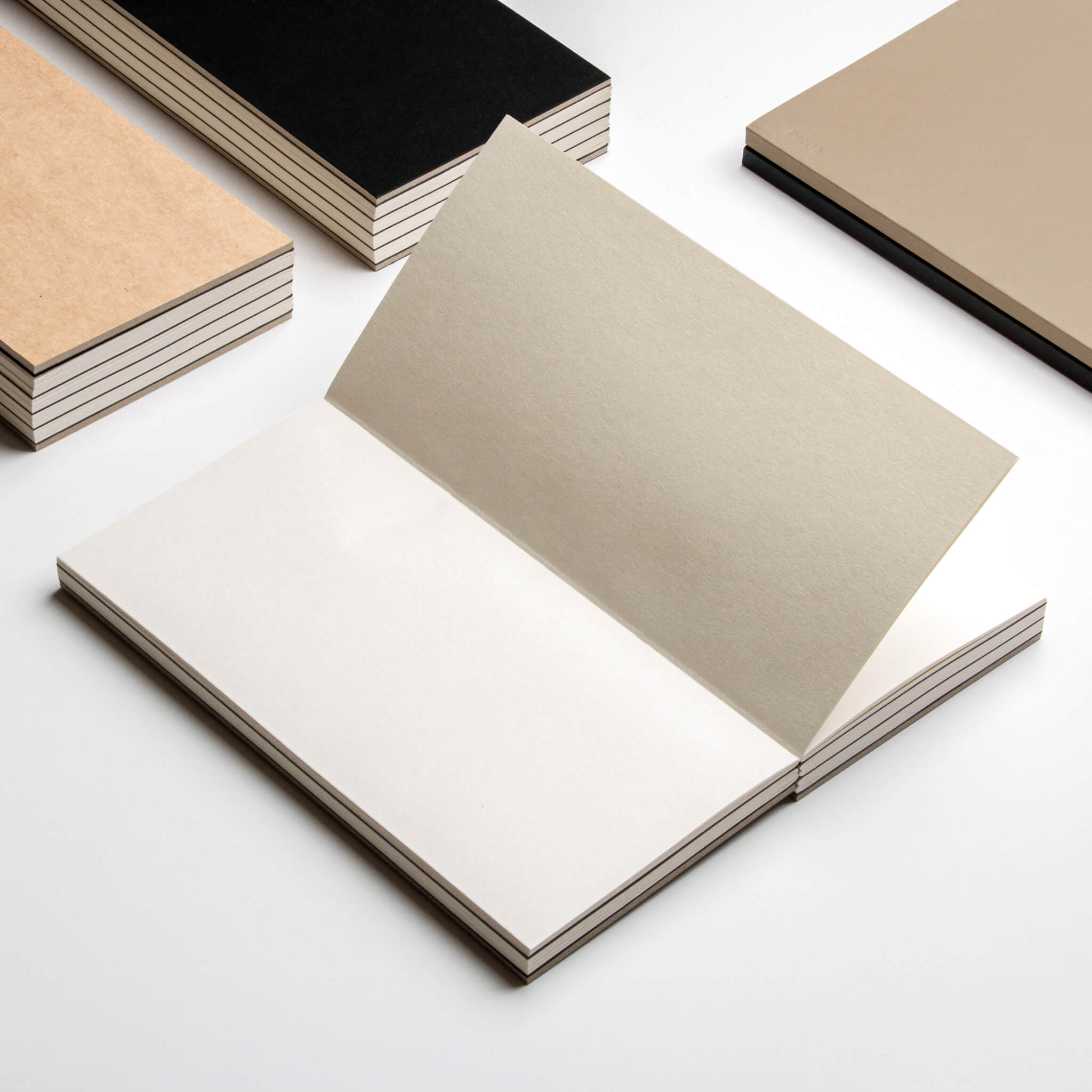 basenotes 1122 Paperbook open flat with Beige cover, surrounded by Black and Kraft variants