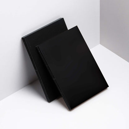 Two basenotes 1623B Black Paper books positioned upright, showing minimalist covers and exposed stitching.