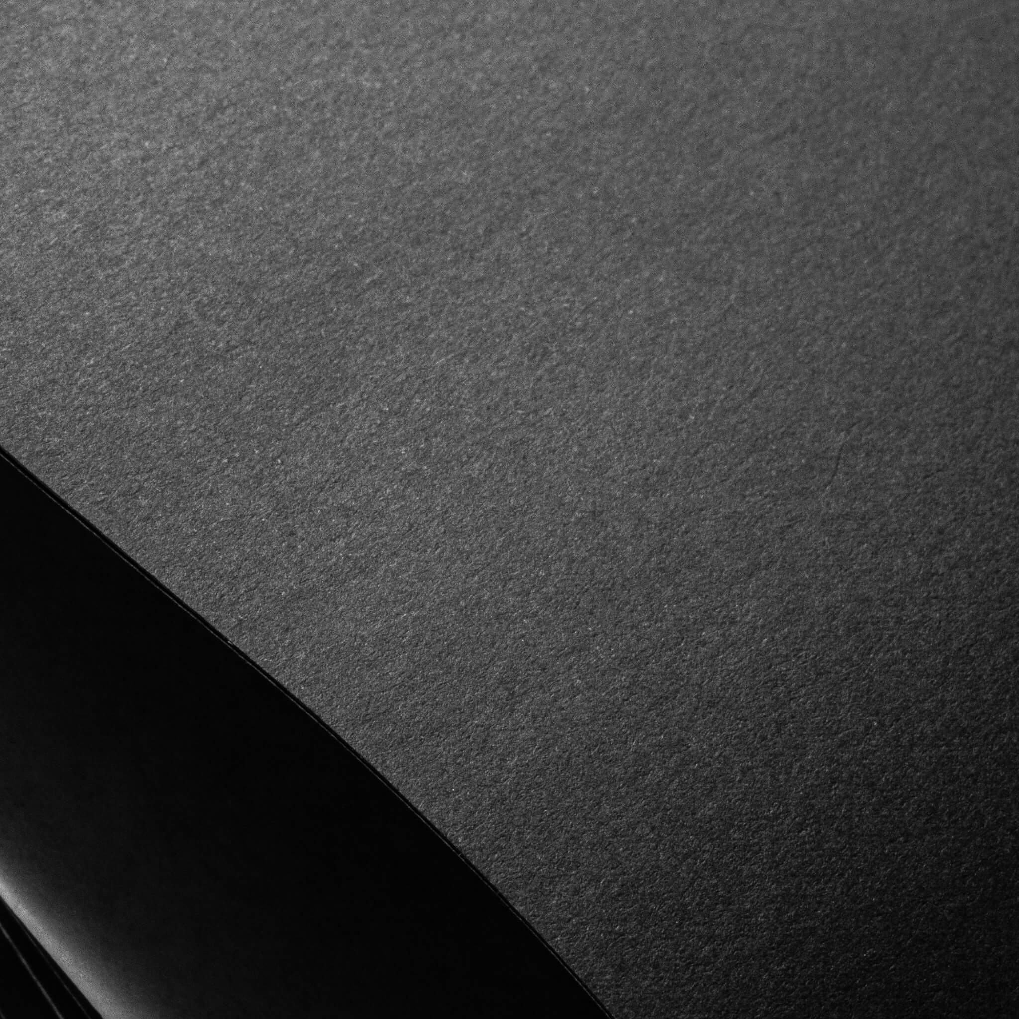 Macro shot of basenotes 2222 Paperbook black matte paper showing natural texture under soft light.