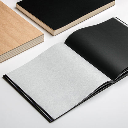 Open basenotes 2222 Paperbook showing black pages interleaved with tracing paper and a kraft notebook beside it.