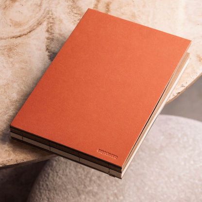 basenotes 2316mk landscape sketchbook with hand-stitched lay-flat binding, featuring a warm orange cover and dual white and kraft acid-free paper.