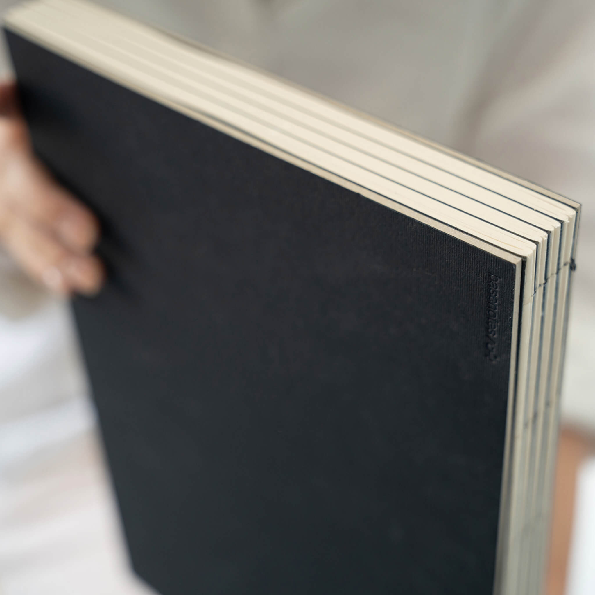 Close-up of the basenotes 2333 Paperbook black cover showing embossed logo and visible hand stitching.