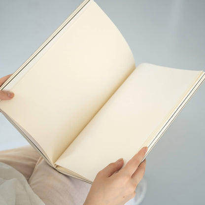 basenotes 2333 Paperbook opened on lap showing cream-toned acid-free pages and hand-stitched spine.