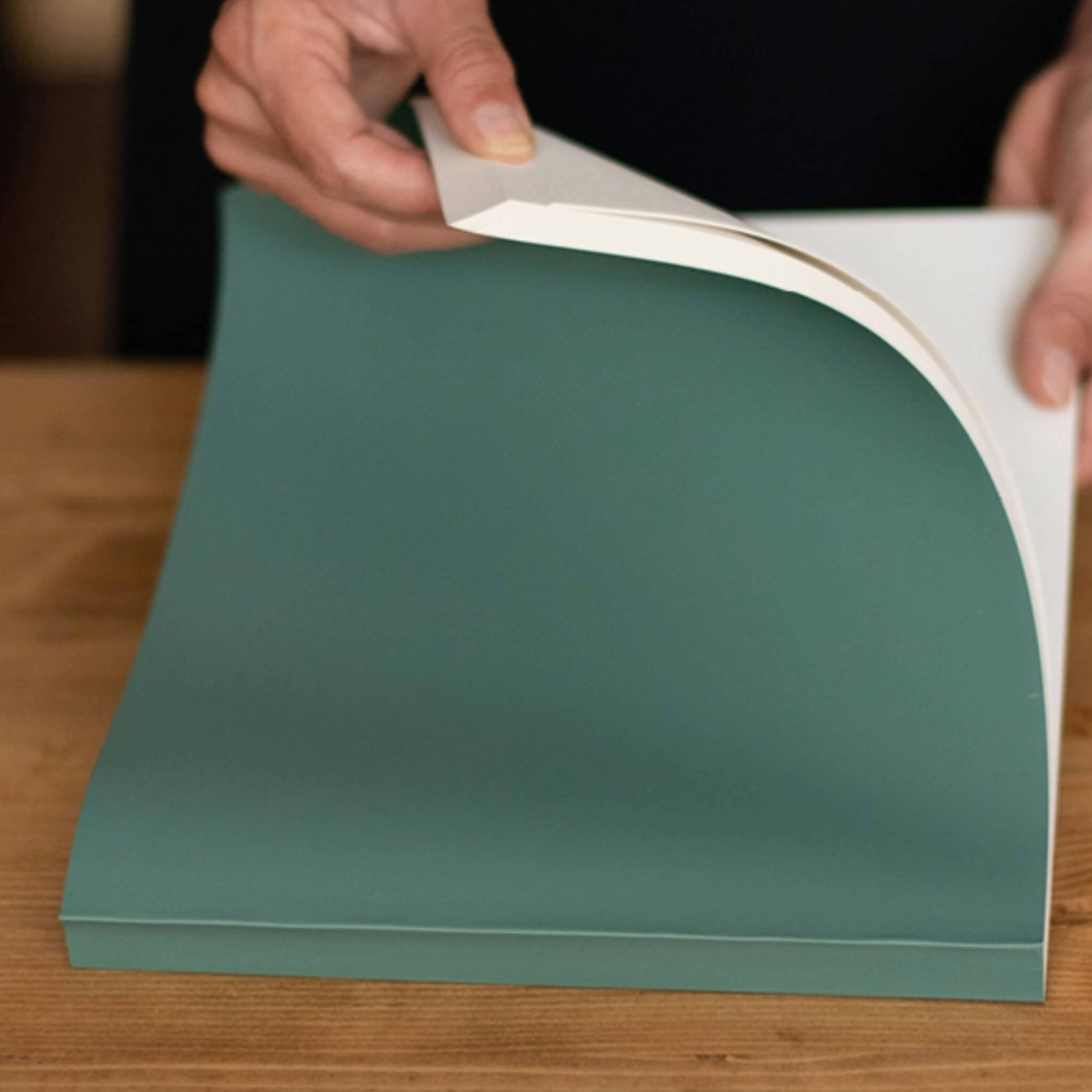Person flipping through a green basenotes 2721 notebook with FSC-certified cream paper and a softcover finish.