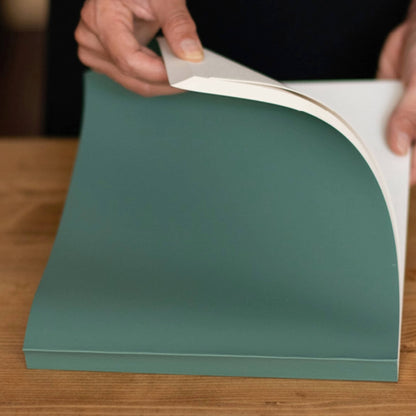 Person flipping through a green basenotes 2721 notebook with FSC-certified cream paper and a softcover finish.