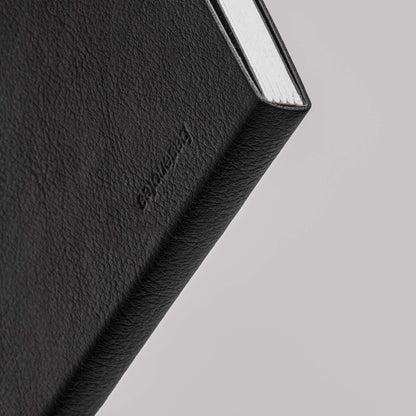 Macro image of the basenotes 4000 A5 Notebook’s spine, showing the embossed Basenotes logo and textured cover material.