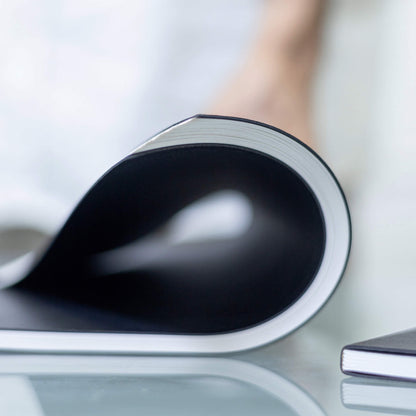 Basenotes 4000 A5 Notebook curved, showcasing flexible lay-flat binding and smooth lined paper ideal for pen writing.