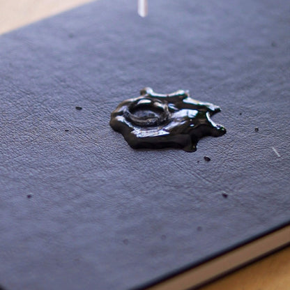 Close-up of the basenotes 4000 A5 Notebook’s waterproof black cover with water droplets demonstrating resistance to liquid.
