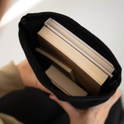 Black fabric notebook cover holding multiple basenotes notebooks in A4 and A5 sizes, shown from above in hand