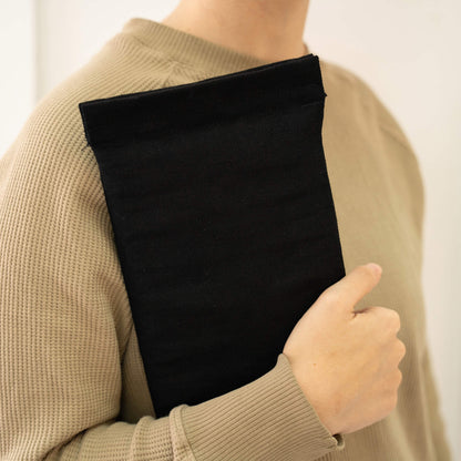 basenotes black fabric notebook cover carried by hand against the body, minimal lifestyle view