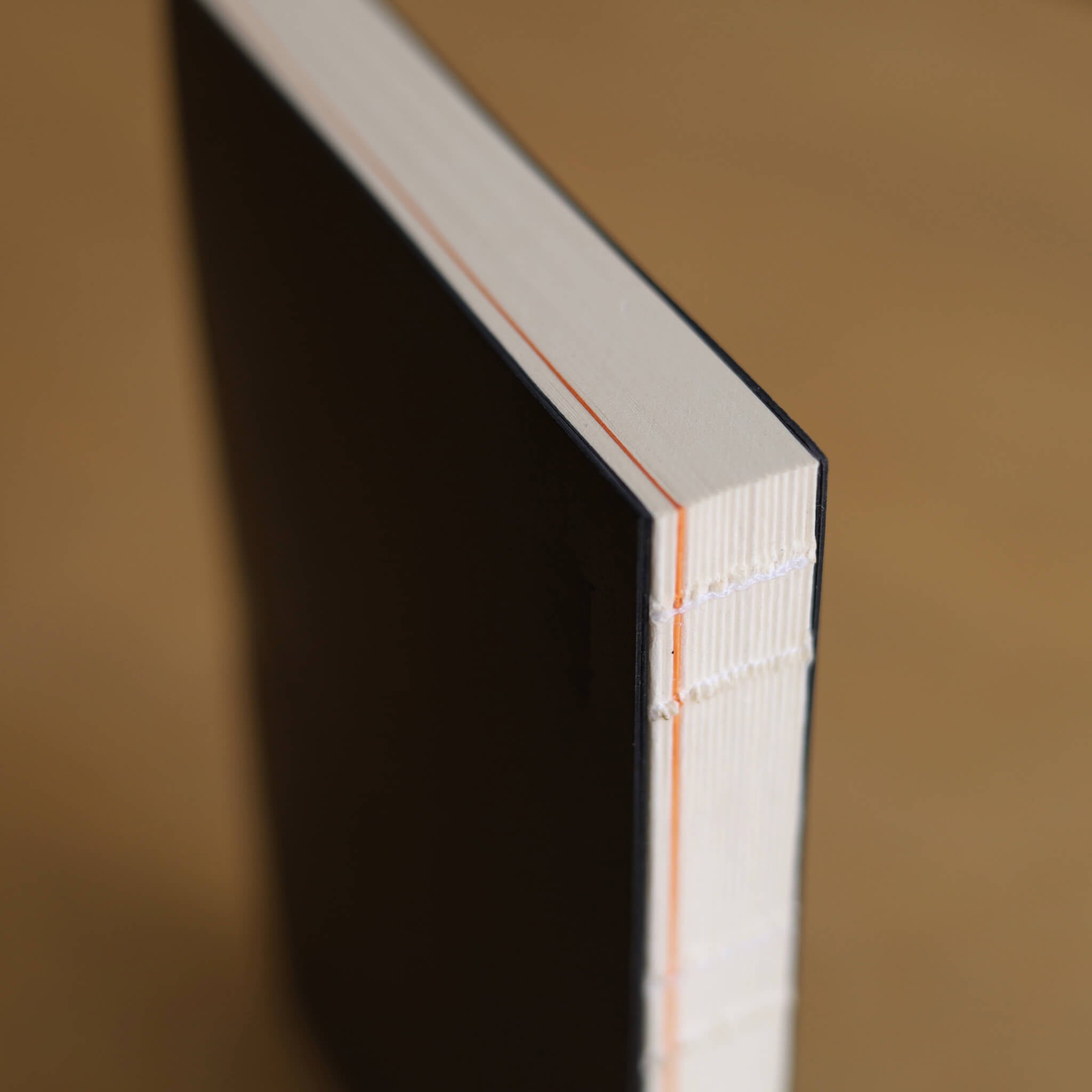 Close-up of the basenotes Planner’s exposed binding with orange stitch detail, showing precision hand-sewn construction and clean edge finish.