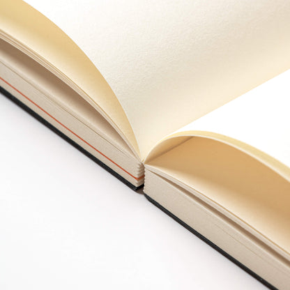 Close-up of the basenotes Planner showing lay-flat stitched binding and smooth cream FSC-certified paper with subtle orange section dividers.