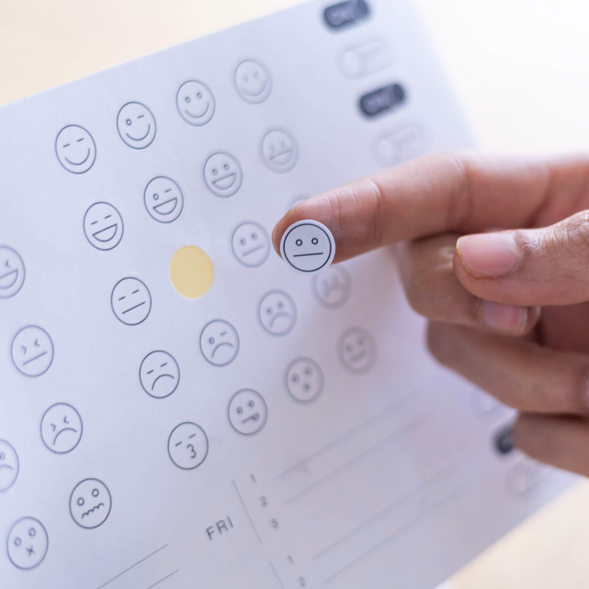 Hand holding a neutral face mood sticker from a minimal icon sticker sheet