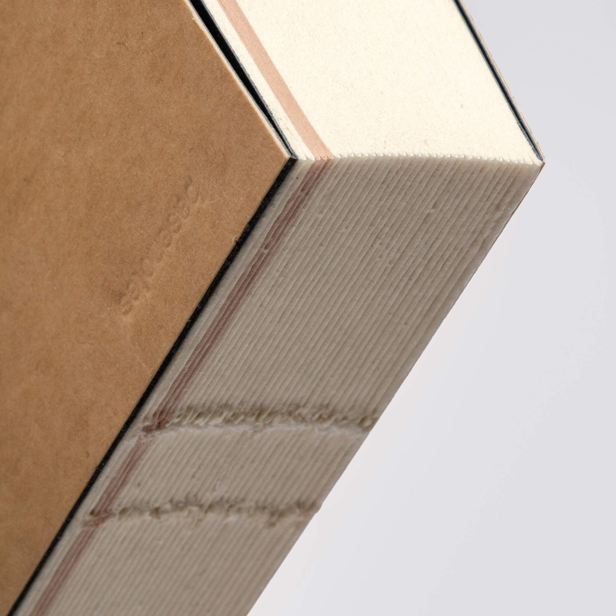 Close-up of basenotes Tracker Notebook spine showing exposed thread stitching and handmade binding detail.