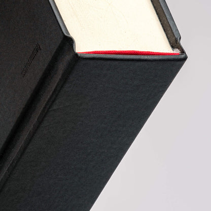 Close-up of basenotes 0512 Notebook handmade spine with red headband detailing, showing artisanal binding and paper grain.