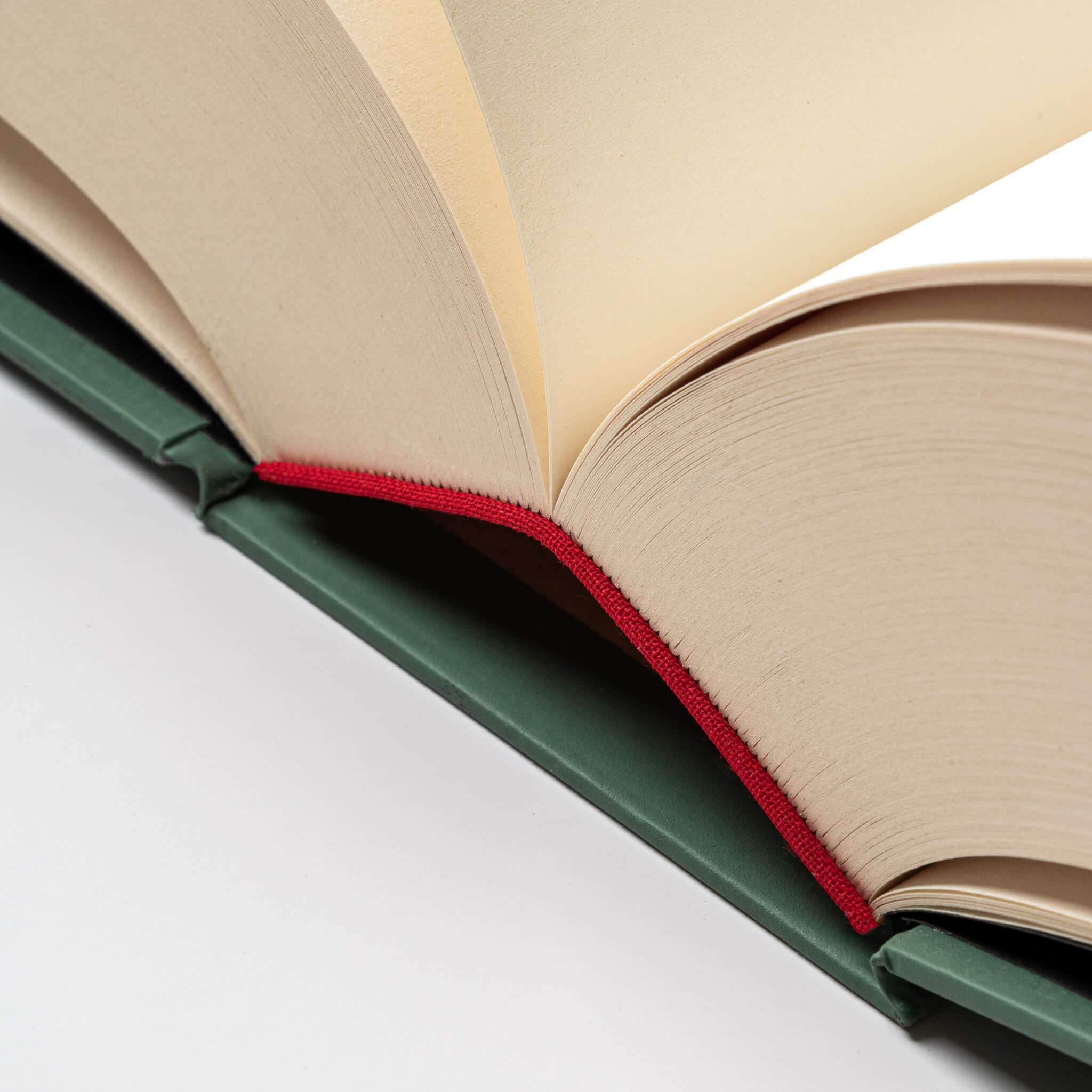 Close-up of the basenotes 0512 Notebook binding in green, featuring the red headband and precision hand-sewn spine, a mark of artisanal craftsmanship.