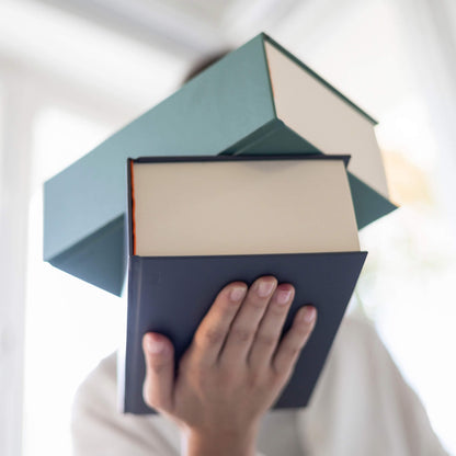 Person holding a stack of basenotes 0512 Notebooks in black and green, emphasising the large-format 1024-page design and solid hardcover.